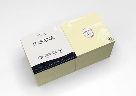 Auf dem Bild ist eine Verkaufsverpackung von Servietten der Marke FASANA in butter-cream in 33x33cm und 1/4 Falzung von schräg oben zu sehen. Bild ©FASANA Verwendung mit freundlicher Genehmigung